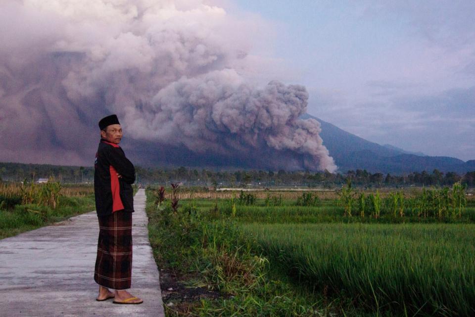 Mandatory Credit: Photo by Uncredited/AP/Shutterstock (13648331b) Man looks on as Mount Semeru releases volcanic materials during an eruption on in Lumajang, East java, Indonesia. Indonesia's highest volcano on the country's most densely populated island of Java erupted Sunday Volcano Eruption, Lumajang, Indonesia - 03 Dec 2022