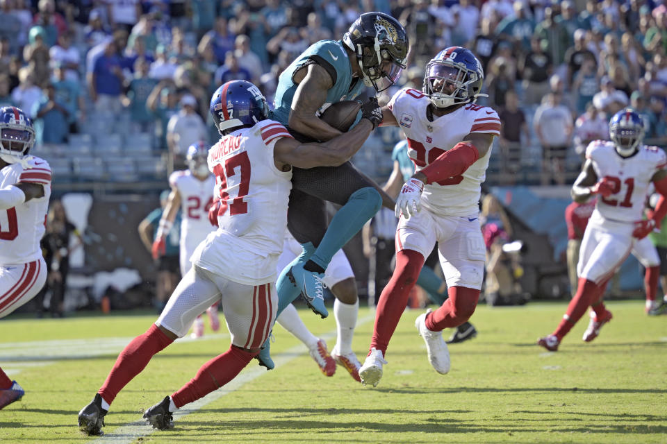 Jacksonville Jaguars wide receiver Christian Kirk (13) is stopped by New York Giants cornerback Fabian Moreau (37) and safety Julian Love (20) during the second half of an NFL football game Sunday, Oct. 23, 2022, in Jacksonville, Fla. (AP Photo/Phelan M. Ebenhack)