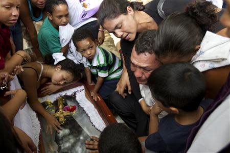 Relatives of a gunshot victim cry over his coffin during his funeral ceremony in Caracas November 27, 2012. REUTERS/Carlos Garcia Rawlins