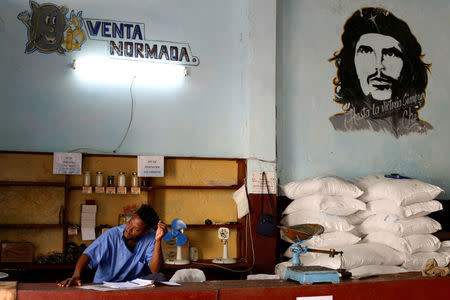 A man works in a subsidised state store, or "bodega", next to an image of late revolutionary hero Ernesto "Che" Guevara in Havana, Cuba July 21, 2018. REUTERS/Stringer