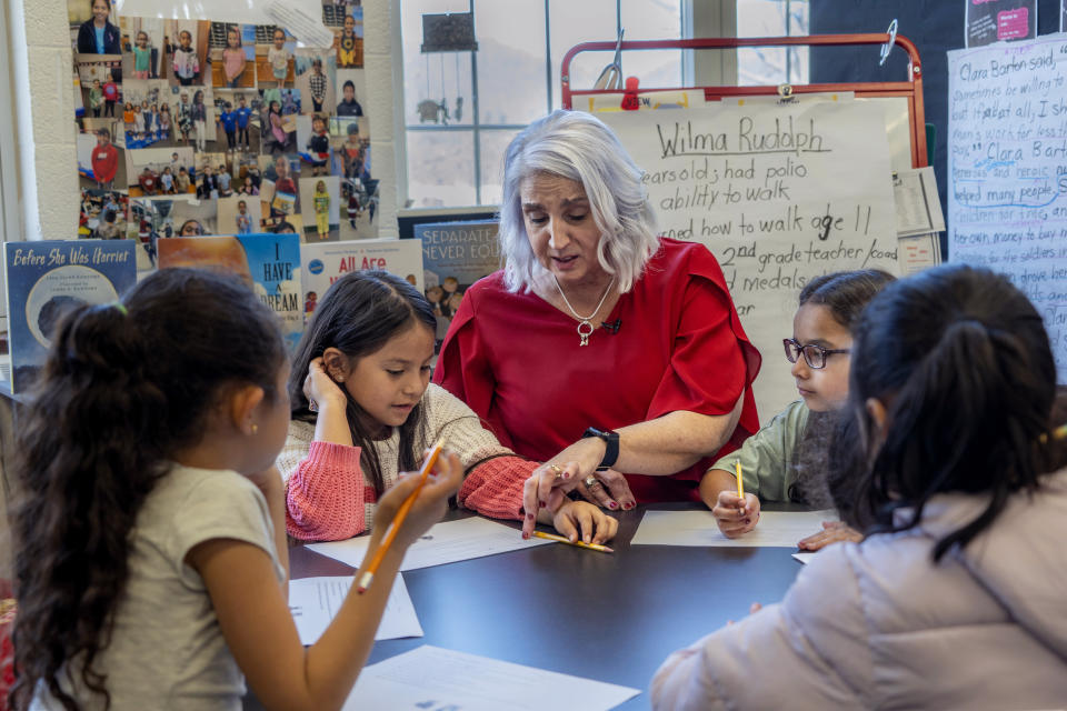 In this photo released Tennessee Department of Education, 2nd grade teacher Missy Testerman, center, who teaches English as a second language, works with students Jana El Kammash, far left, Dafne Lozano, Dwiti Patel, and Ana Corea, far right, at the Rogersville City School, Thursday, March 13, 2024, in Rogersville, Tenn. Testerman has been named the 2024 National Teacher of the Year by the Council of Chief State School Officers. (Tennessee Department of Education via AP)