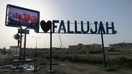 A candidate's poster lies on the ground near an "I love Falluja" sign during an Iraqi parliamentary election in Falluja, Iraq May 12, 2018. REUTERS/Ahmed Aboulenein