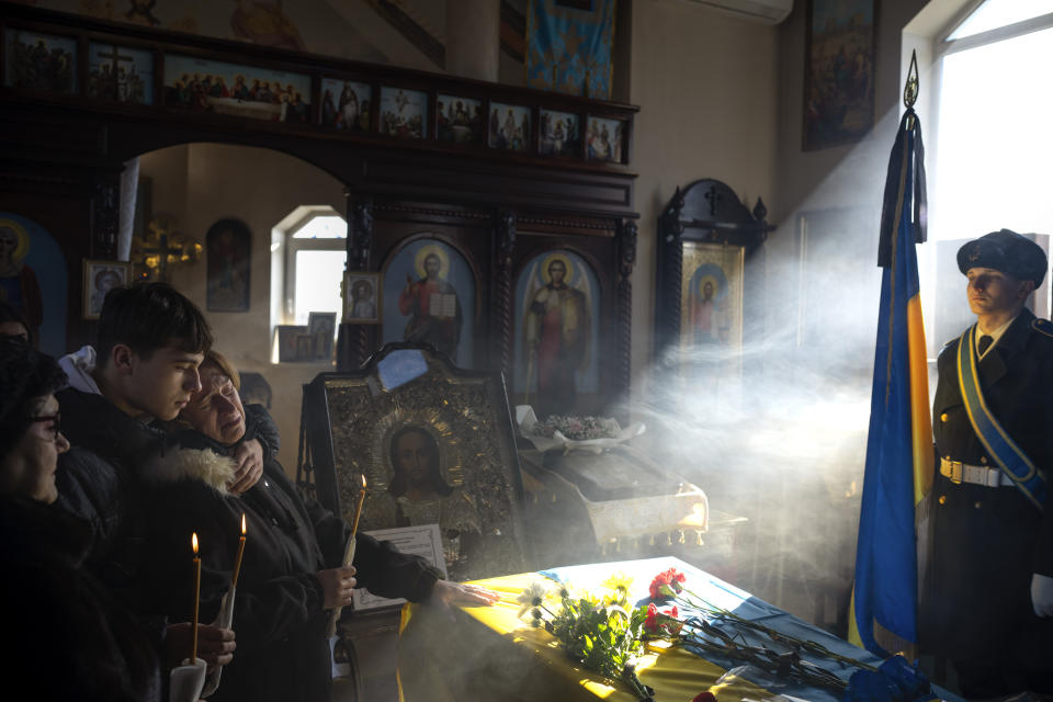 Svitlana with her son Kyrylo, reacts next to the coffin of her husband Serhii, 48, during his funeral in Tarasivka village, near Kyiv, Ukraine, Wednesday, Feb. 15, 2023. Serhii Havryliuk, an officer of the Azov Assault Brigade, died while defending the Azovstal steel plant in Mariupol on April 12, 2022 against the Russians. Serhii has finally been buried after DNA tests confirmed his identity. (AP Photo/Emilio Morenatti)