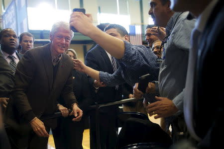 Former U.S. President Bill Clinton poses for a photograph with an audience member while campaigning for his wife, U.S. Democratic presidential candidate Hillary Clinton, in Nashua, New Hampshire, January 4, 2016. REUTERS/Brian Snyder