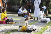 Balinese Hindu pray spaced apart amid concerns of the new coronavirus outbreak during a Hindu ritual in Bali, Indonesia Saturday, July 4, 2020. (AP Photo/Firdia Lisnawati)