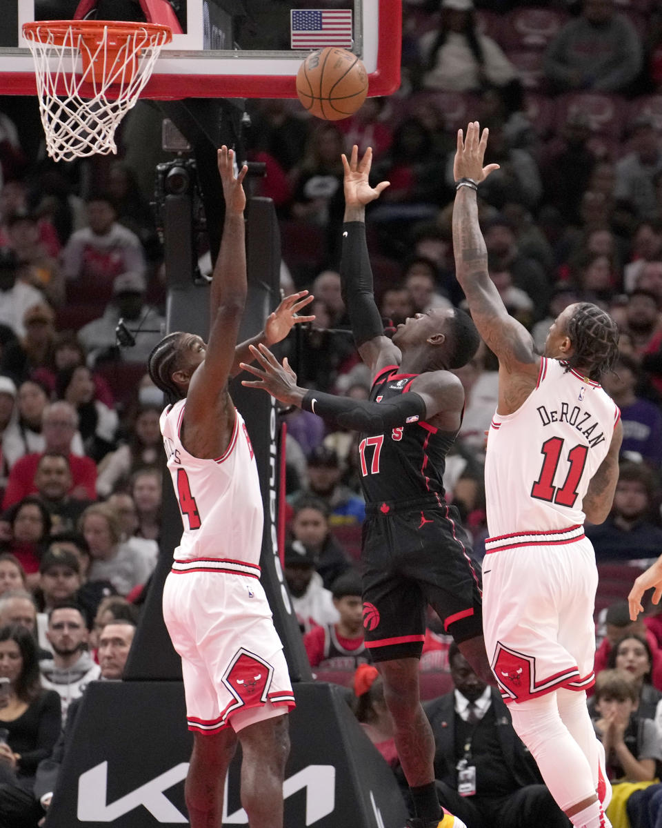 Toronto Raptors' Dennis Schroder (17) scores between Chicago Bulls' Patrick Williams, left, and DeMar DeRozan (11) during the first half of an NBA basketball game Friday, Oct. 27, 2023, in Chicago. (AP Photo/Charles Rex Arbogast)