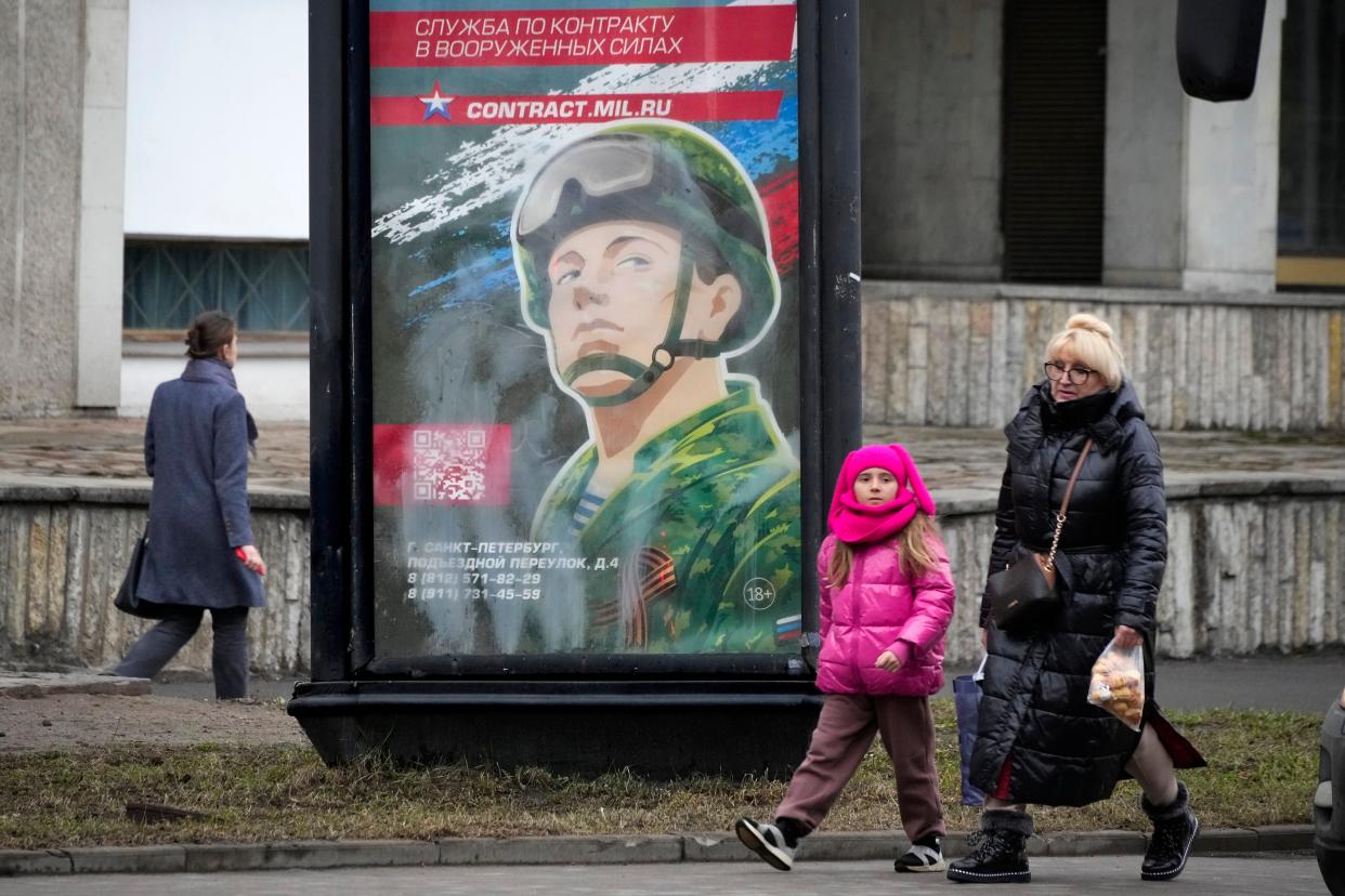 People walk past an army recruiting billboard with the words “Military service under contract in the armed forces” in St. Petersburg, Russia (Copyright 2023 The Associated Press. All rights reserved)