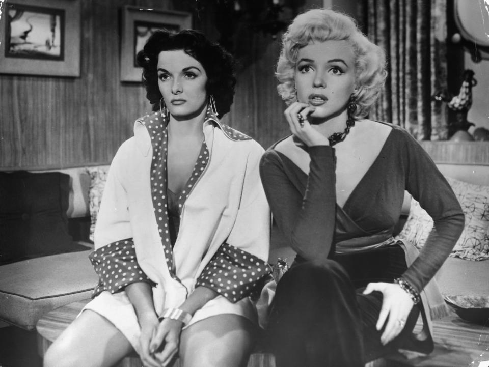 Jane Russell and Marilyn Monroe sitting on table together in a scene from the film 'Gentlemen Prefer Blondes', 1953. (Photo by 20th Century-Fox/Getty Images)