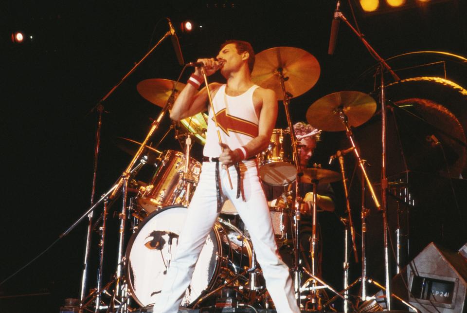 Freddie Mercury (1946-1991), singer with Queen, standing in front of a drumkit as he sings into a microphone on stage during a live concert performance by the band at the National Bowl in Milton Keynes, England, United Kingdom, on 5 June 1982.