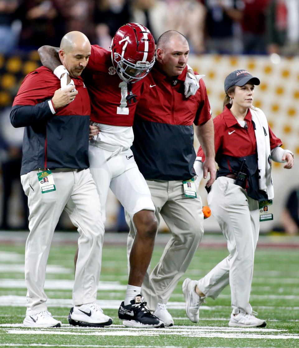 Jameson Williams (1) is helped off the field after suffering a knee injury during the College Football Playoff national championship at Lucas Oil Stadium in Indianapolis.