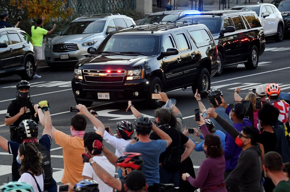 TOPSHOT - People react as the motorcade carrying US President Donald Trump returns to the White House on November 7, 2020 in Washington, DC., after Joe Biden was declared the winner of the 2020 presidential election. - Joyous celebrations erupted in Washington on Saturday after Joe Biden was declared winner of the US presidency, as several people poured into the streets of the US capital -- some of them chanting, cheering and singing in front of the White House. (Photo by Olivier DOULIERY / AFP) (Photo by OLIVIER DOULIERY/AFP via Getty Images)