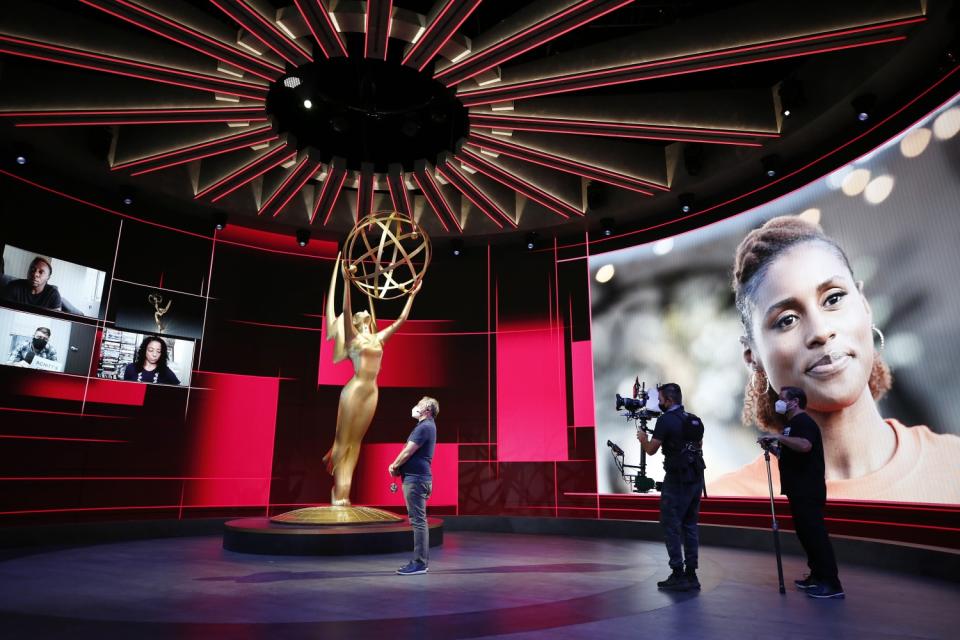 Stage manager Gary Natoli stands center stage. A screen at right pictures Issa Rae.