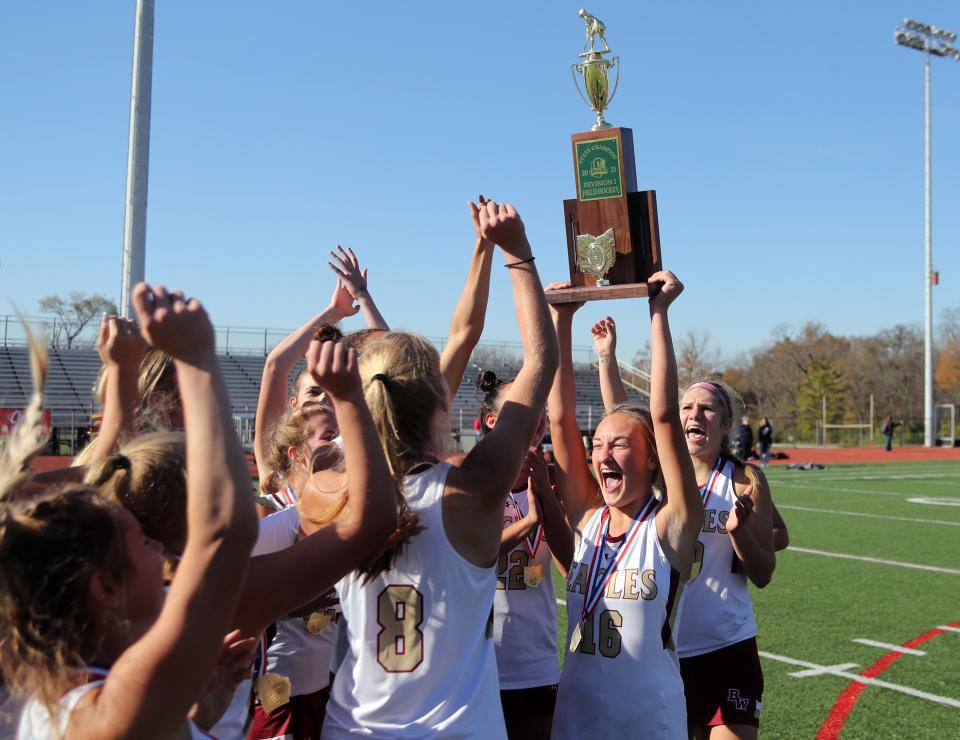 Watterson's Grace Cantwell hoists up the field hockey state championship trophy and celebrates with teammates after defeating Thomas Worthington, 2-1, in overtime during the OHSAA Field Hockey State Final game Nov. 6, 2021, at Thomas Worthington High School in Worthington, Ohio.