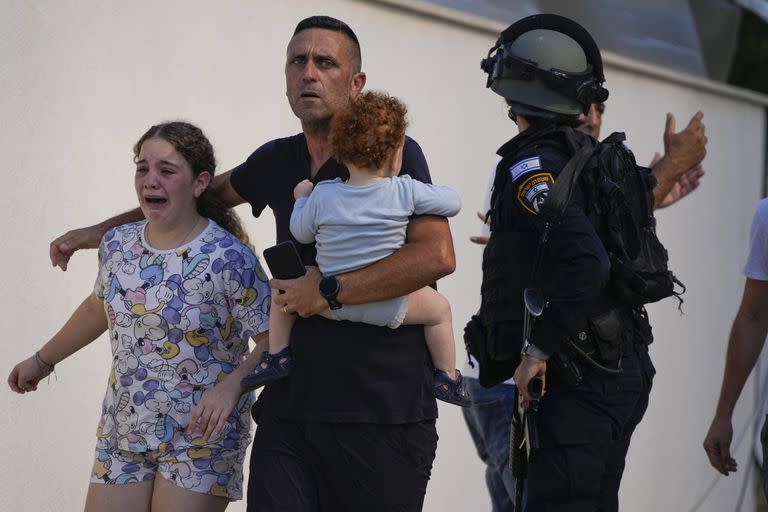 Agentes de policía israelíes evacuan a una familia de un lugar alcanzado por un cohete disparado desde la Franja de Gaza, en Ashkelon, sur de Israel, el sábado 7 de octubre de 2023. 