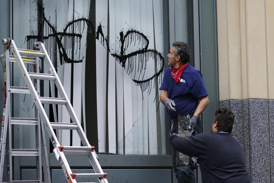 Workers remove a broken window from the Ronald V. Dellums Federal Building in Oakland, Calif., Sunday, July 26, 2020. A protest through the streets of downtown Oakland, California Saturday night in support of racial justice and police reform turned violent when "agitators" among the demonstrators set fire to a courthouse, vandalized a police station and shot fireworks at officers, authorities said. (AP Photo/Jeff Chiu)