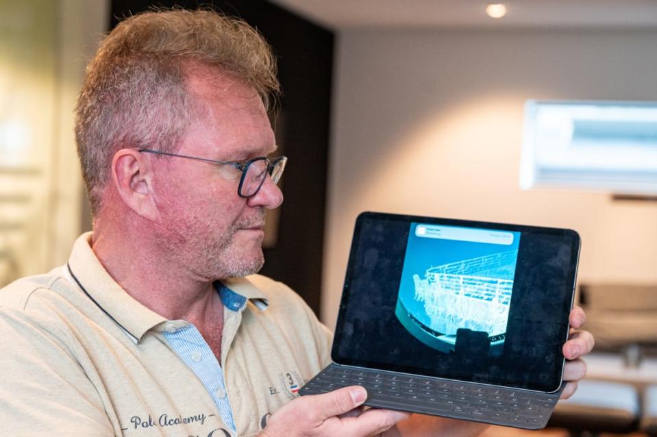 Arthur Loibl, a former passenger on the Titan, stands in his house with a tablet showing a photo of the Titanic. In 2021, he was one of the first passengers to descend to the Titanic in a mini-submarine operated by Oceangate Expeditions.