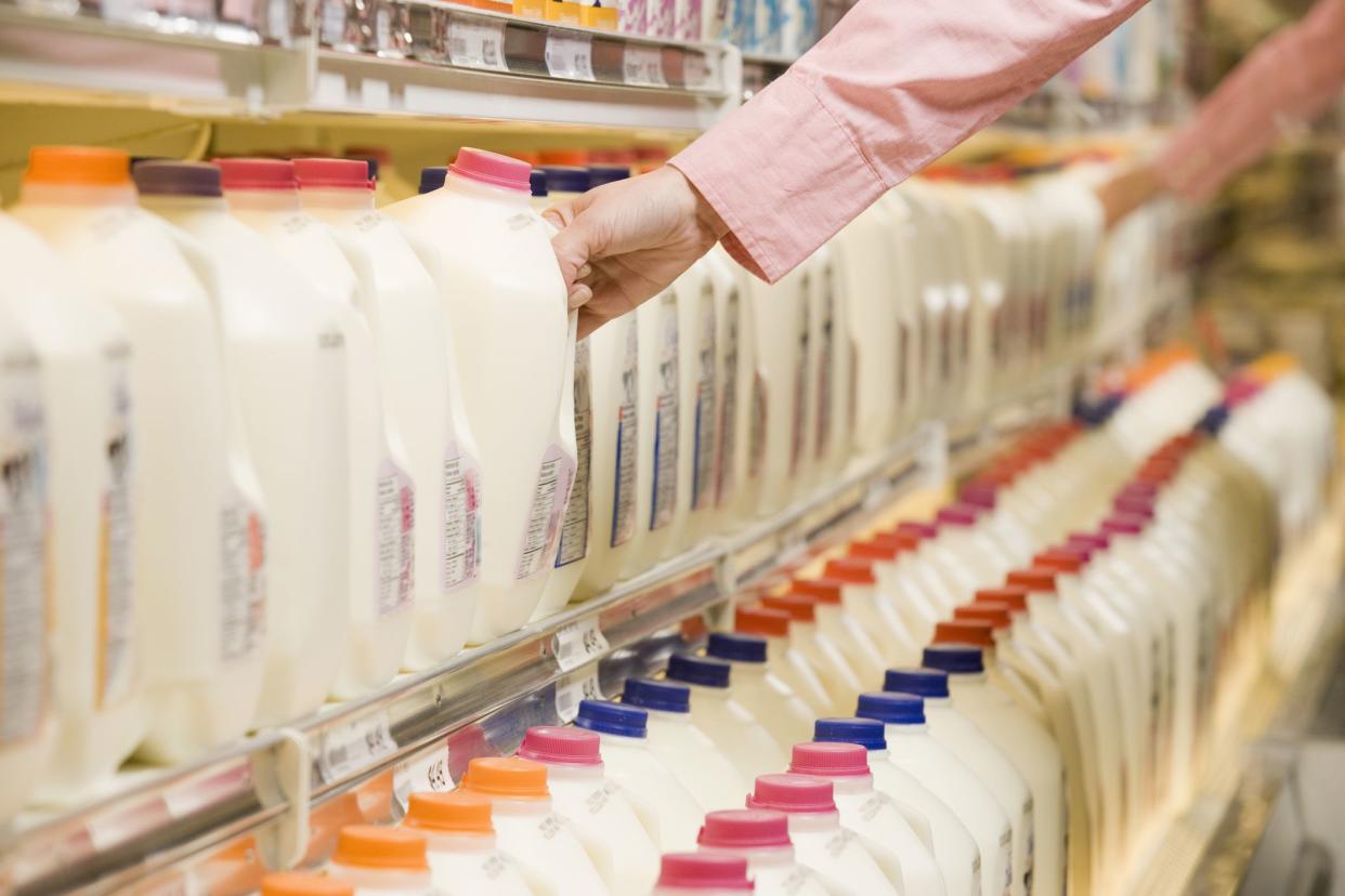 Woman selecting milk from dairy aisle in supermarket