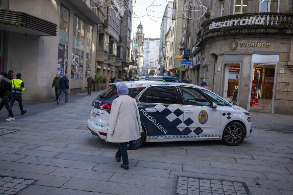 A small police vehicle turns past a pedestrian in Pontevedra's city center.