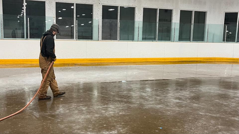 Rink workers say they have had to work odd hours and use creative solutions to set and maintain the ice. Pictured here, one rink volunteer floods the ice in late November.
