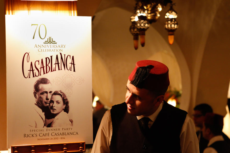 A Rick's Cafe's server looks at the poster announcing the 70th anniversary tribute to the 1942 movie "Casablanca" , in Casablanca, Morocco, Saturday, Nov. 24, 2012. A former U.S. diplomat spent two years of work and a million dollars in investments to bring Rick's Cafe to Morocco's largest city. The elegant nightclub where Humphrey Bogart pined for Ingrid Bergman was just a set on a Warner Bros. sound stage in California, the film crew never got anywhere near North Africa. (AP Photo/Abdejalil Bounhar)