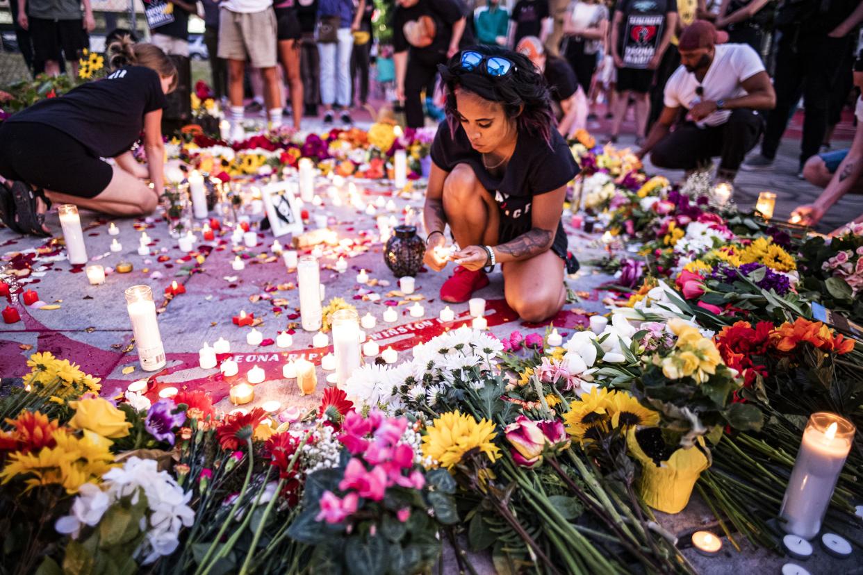 Nae Totushek lights candles in honor of Deona Knajdek late Monday.