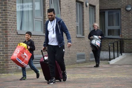 A priest helps a family move from the Dorney Tower residential block during an evacuation as a precautionary measure following concerns over the type of cladding used on the outside of the building on the Chalcots Estate in north London, Britain, June 24, 2017. REUTERS/Hannah McKay