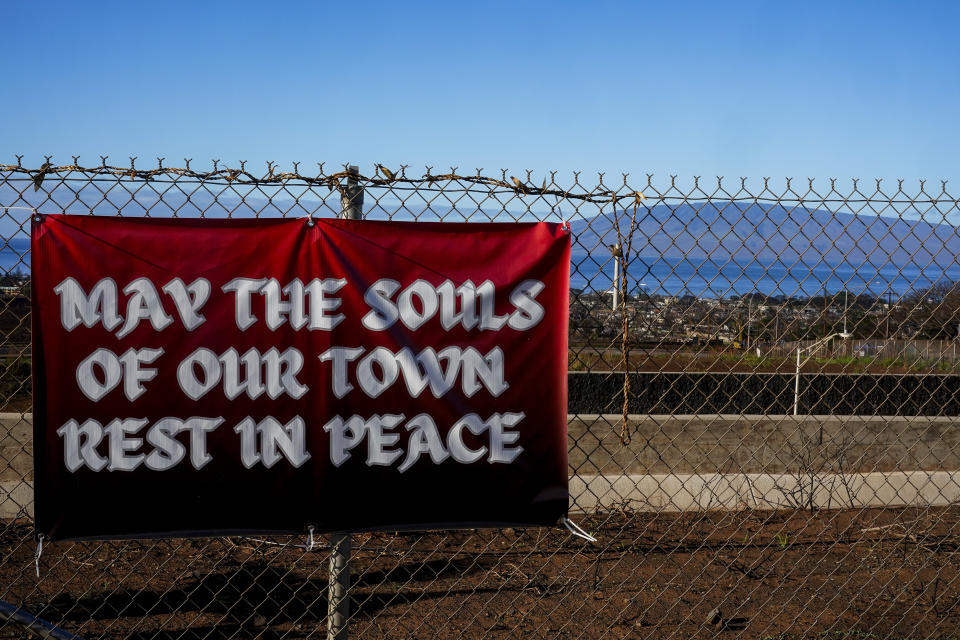 A sign for victims of a deadly wildfire hangs over the Lahaina Bypass highway, Wednesday, Dec. 6, 2023, in Lahaina, Hawaii. Recovery efforts continue after the August wildfire that swept through the Lahaina community on Hawaiian island of Maui, the deadliest U.S. wildfire in more than a century. (AP Photo/Lindsey Wasson)