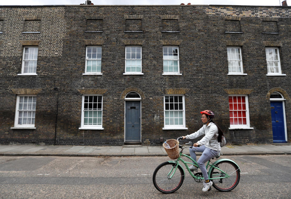 A cyclist rides past terraced houses built in the 19th century in a conservation area of London, Britain