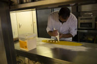 Chef Kayes Ghourabi works in the kitchen as he prepares take-away meals in his restaurant, Tartufo, in Sint-Pieters-Leeuw, Belgium, Thursday, Oct. 22, 2020. The coronavirus pandemic is gathering strength again in Europe and, with winter coming, its restaurant industry is struggling. The spring lockdowns were already devastating for many, and now a new set restrictions is dealing a second blow. Some governments have ordered restaurants closed; others have imposed restrictions curtailing how they operate. (AP Photo/Francisco Seco)