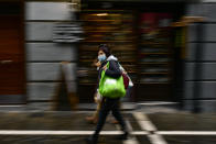 A woman wears a face mask to protect aginst coronaviris, while walking along a street during an autumn day, in Pamplona, northern Spain, Saturday, Oct. 3, 2020. (AP Photo/Alvaro Barrientos)