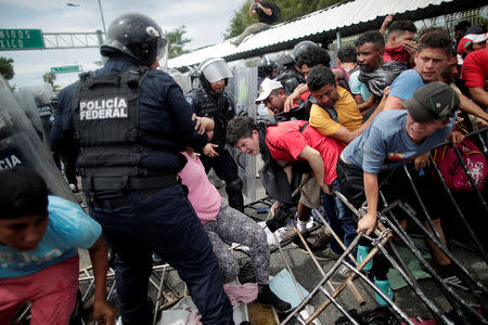 Honduran migrants, part of a caravan trying to reach the U.S., are pushed by other migrants after storming the Guatemalan checkpoint to enter Mexico, in Ciudad Hidalgo, Mexico October 19, 2018. REUTERS/Ueslei Marcelino