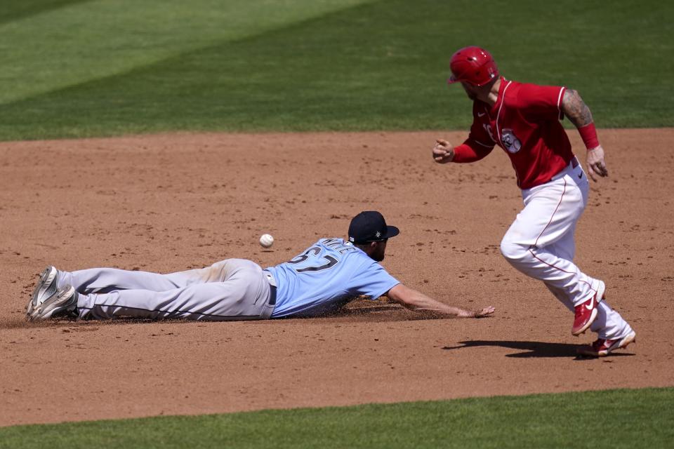 Cincinnati Reds' Tucker Barnhart, right, watches a single hit by Reds' Mark Payton get past Seattle Mariners third baseman Jantzen Witte (67) during the fifth inning of a spring training baseball game Monday, March 29, 2021, in Goodyear, Ariz. (AP Photo/Ross D. Franklin)