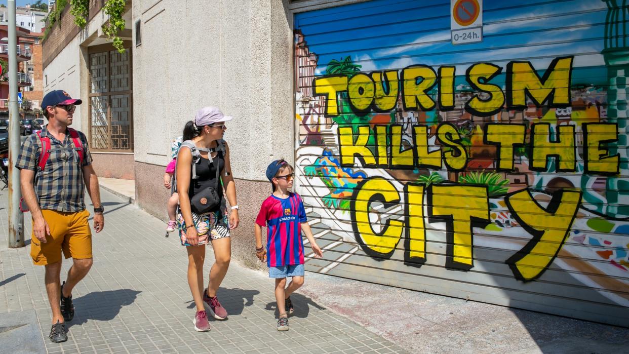  A visiting family walks past anti-tourism graffiti against tourism in Barcelona. 