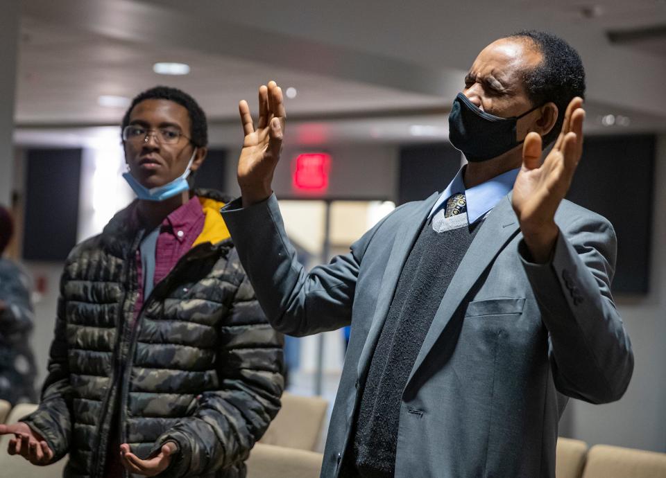 Mengsteab Aregay Gebremariam (right) and his 14-year-old son Mikias listen to worship music at the start of Sunday service at Lakeview Church on Jan. 16, 2022, in Indianapolis. Gebremariam and his wife immigrated to the United States from Eritrea more than a decade ago. 
