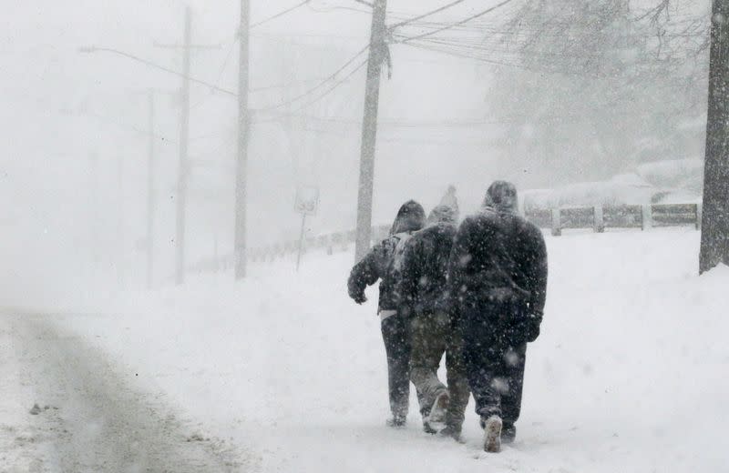 FILE PHOTO: Pedestrians walk through a winter snow storm on New Hampshire Avenue in the Washington suburb of Silver Spring, Maryland