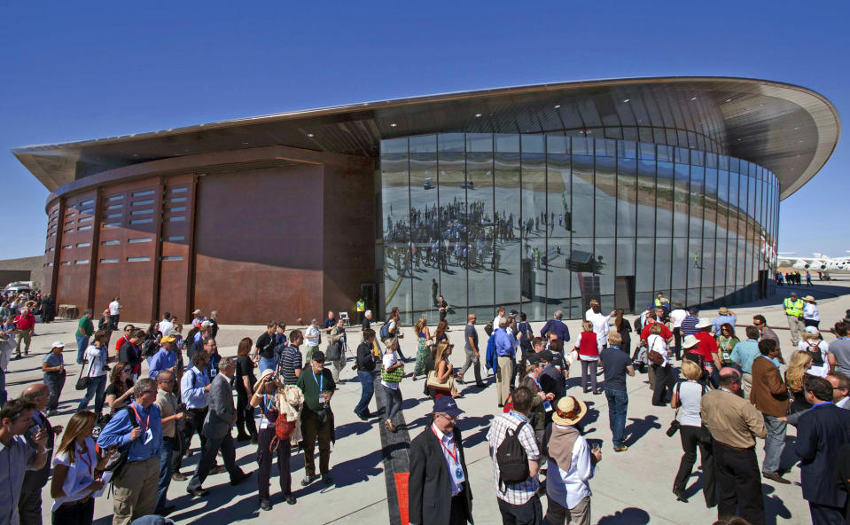 FILE - In this Oct. 17, 2011 file photo, guests stand outside the new Spaceport America hangar in Upham, N.M. Boeing plans to invest $20 million in Virgin Galactic as the space tourism company nears its goal of launching passengers on suborbital flights. The companies announced the investment Tuesday, Oct. 8, 2019, saying they will work together on broadening commercial access to space and transforming global travel technologies. Virgin Galactic has conducted successful test flights of its winged rocket ship at Mojave, California, and is preparing to begin operations at Spaceport America in New Mexico. (AP Photo/Matt York, File)