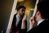 Cayan Hakiki applies make-up in front of a mirror at their home in Ankara