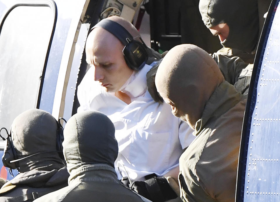 A man in a white overall is escorted by Police officers as he arrives at the federal prosecutor's office in Karlsruhe, Germany, Thursday, Oct. 10, 2019. A German prosecutor says the suspect in Wednesday’s attack in the German city of Halle wanted to carry out a 'massacre' in a synagogue. (Uli Deck/dpa via AP)