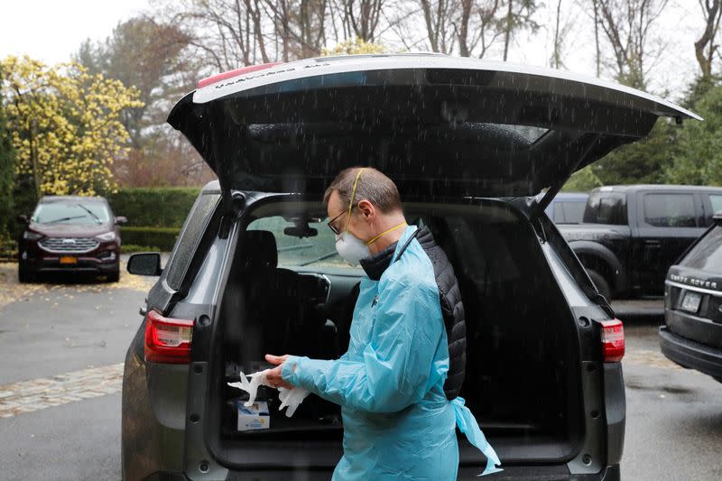 Dr Greg Gulbransen dons personal protective gear for a home call with a patient who had earlier been confirmed to have the coronavirus disease (COVID-19) as he maintains visits with both his regular patients and those with the virus in Oyster Bay, New York