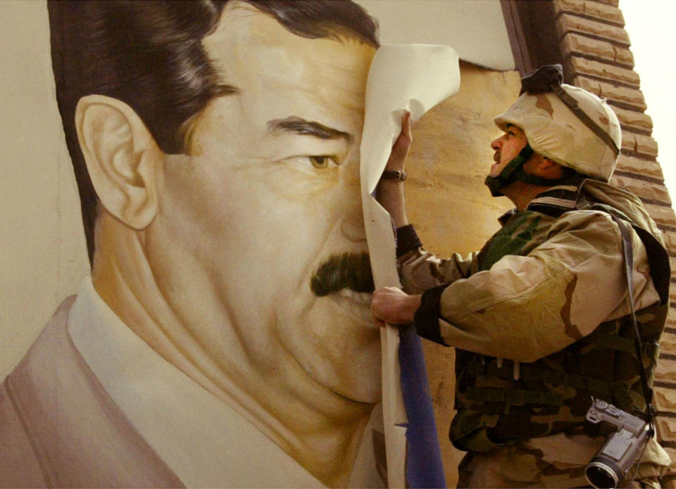 Maj. Bull Gurfein rips a poster from a wall showing the face of Iraqi President Saddam Hussein.