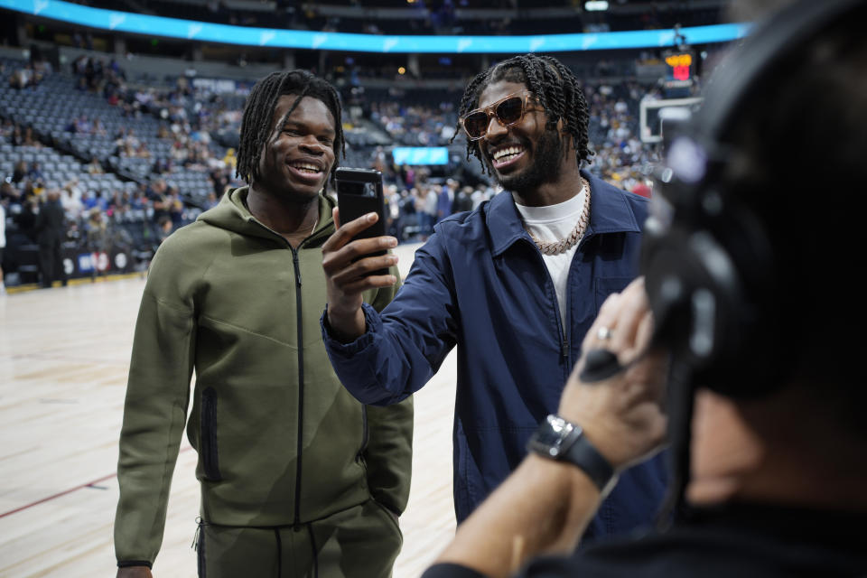 Colorado wide receiver Travis Hunter, left, jokes with quarterback Shedeur Sanders before the Denver Nuggets' NBA basketball game against the Los Angeles Lakers on Tuesday, Oct. 24, 2023, in Denver. (AP Photo/David Zalubowski)