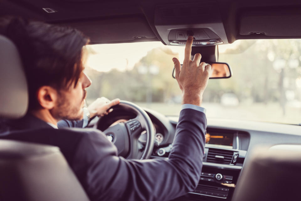 Businessman traveling in car and pressing the car assistance button