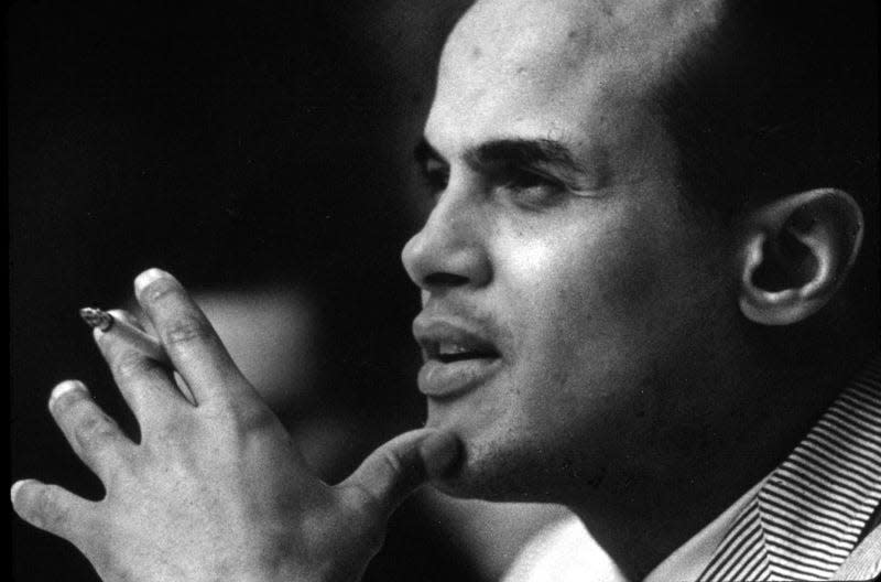  Harry Belafonte smoking a cigarette during an interview.