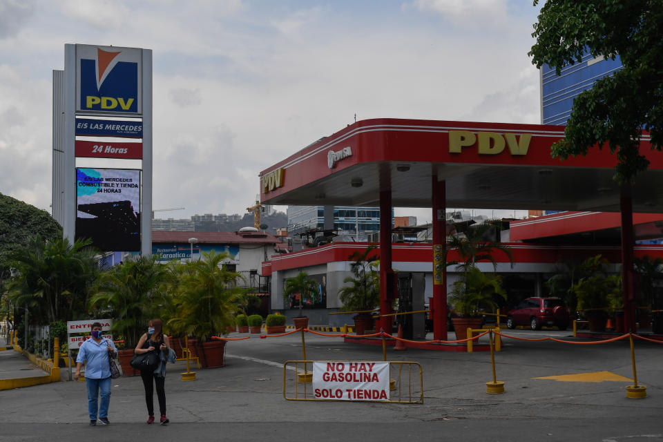 People walk pass a gas station with a sign reading 'No gasoline. Only store' due to the lack of oil in Caracas, on May 14, 2020 amid the novel coronavirus (COVID-19) outbreak. - Maduro's government claims to have contained the spread of the new coronavirus in Venezuela, but maintains without changes the quarantine declared two months ago. According to analysts, the reason goes beyond the pandemic: an aggravated gasoline shortage that prevents reactivating the economy. (Photo by Federico PARRA / AFP) (Photo by FEDERICO PARRA/AFP via Getty Images)