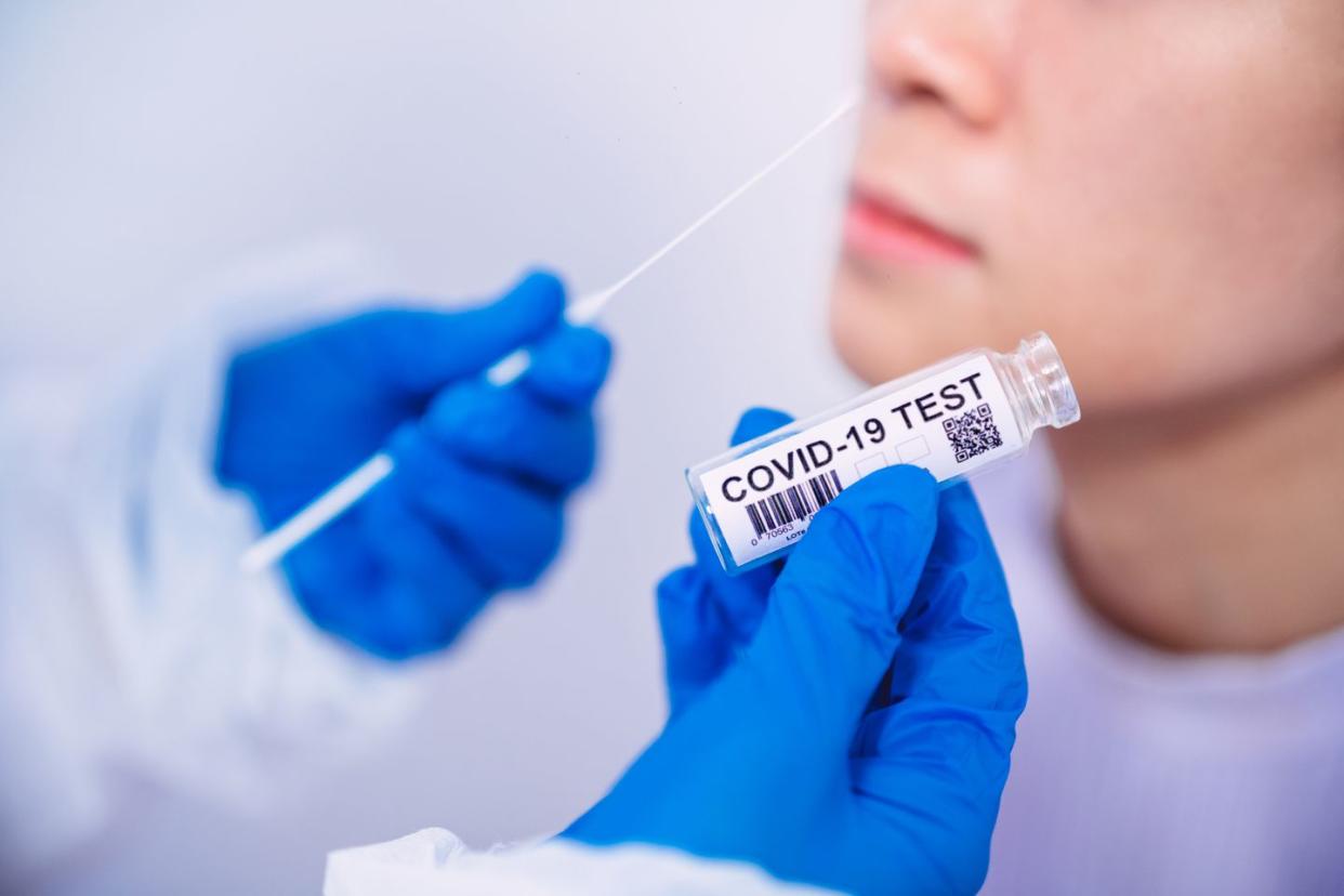 doctor in protective gloves workwear holding testing kit for the coronavirus test