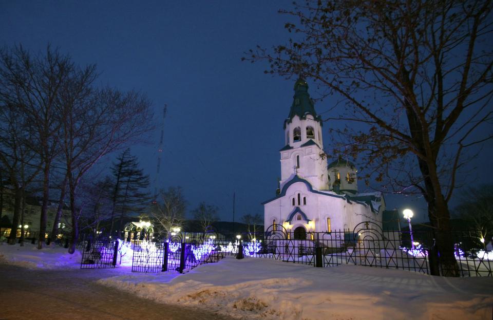 The Cathedral of the Resurrection of Christ in Yuzhno-Sakhalinsk is illuminated on Sunday, Feb. 9, 2014. Law enforcement officers detained the man, who worked as a security guard, and were trying to determine why he attacked the Russian Orthodox cathedral in the city of Yuzhno-Sakhalinsk, the federal Investigative Committee said in a statement. A gunman opened fire Sunday in a cathedral on Russia's Sakhalin Island in the Pacific, killing a nun and a parishioner and wounding six others, investigators said. Concerns about security in Russia are especially high because of the Winter Olympics in Sochi, but there was no apparent connection to the games. Sakhalin Island is about 7,500 kilometers (more than 4,500 miles) from Sochi. (AP Photo/ Dmitriy Sindyakov)