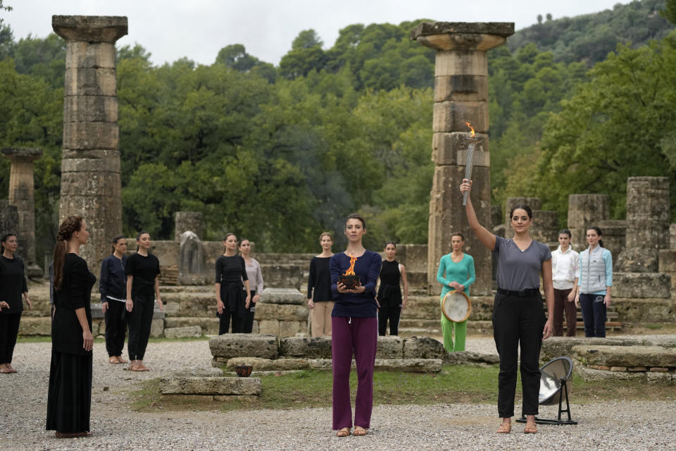 Greek actress Xanthi Georgiou, playing the role of the High Priestess, holds up the torch during the final rehearsal for the lighting of the Olympic flame at Ancient Olympia site, birthplace of the ancient Olympics in southwestern Greece, Sunday, Oct. 17, 2021. The flame will be transported by torch relay to Beijing, China, which will host the Feb. 4-20, 2022 Winter Olympics. (AP Photo/Thanassis Stavrakis)