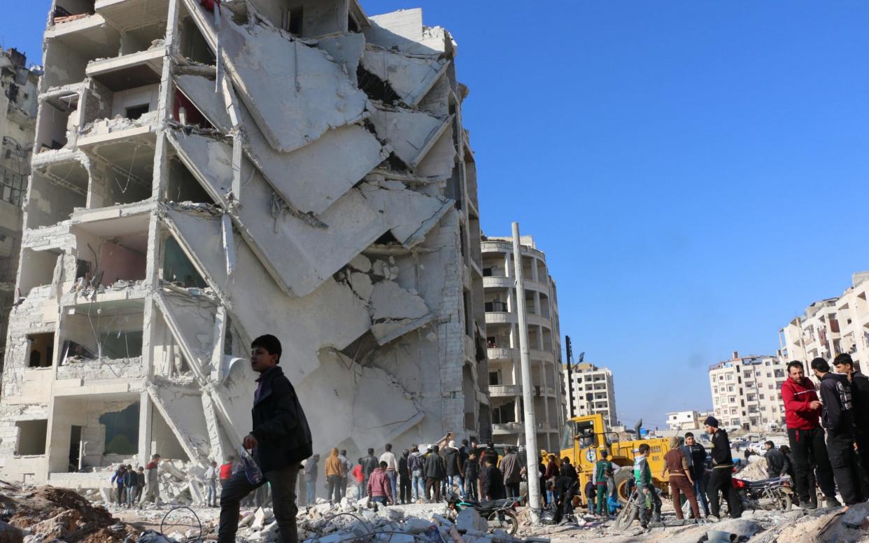 People inspect the damaged buildings after explosions were carried out with bomb-laden vehicles in Idlib, Syria  - Anadolu