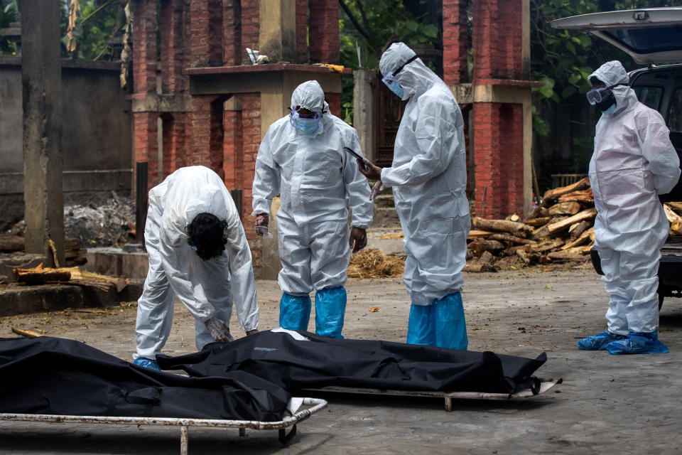 Relatives in protective suits prepare to cremate the body of a person who died of COVID-19 in Gauhati, India, Monday, May 24, 2021. India crossed another grim milestone Monday of more than 300,000 people lost to the coronavirus as a devastating surge of infections appeared to be easing in big cities but was swamping the poorer countryside. (AP Photo/Anupam Nath)