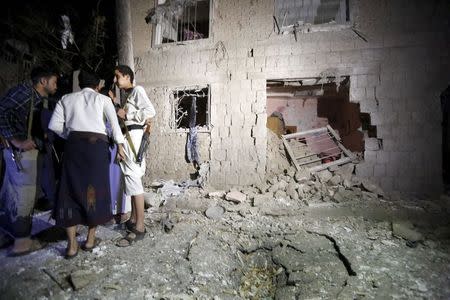 People stand next to a damaged house at the site of a car bomb attack in Yemen's capital Sanaa June 29, 2015. REUTERS/Khaled Abdullah